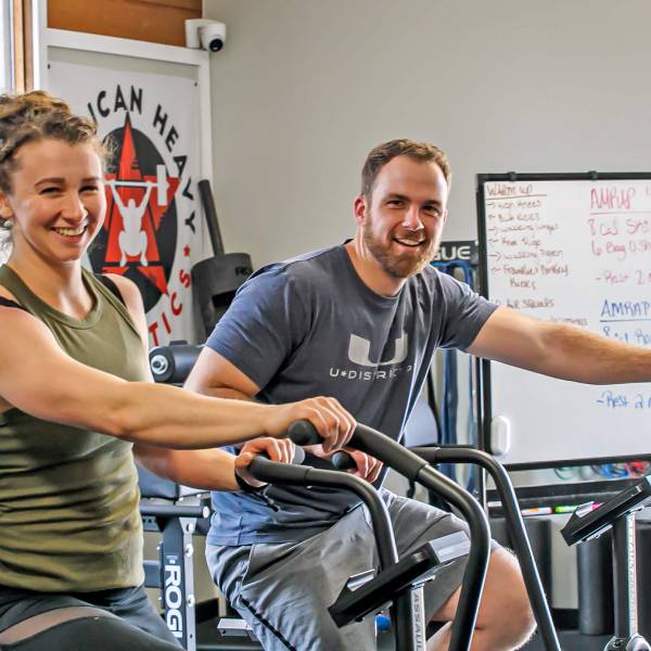 Two people smiling during their class on exercise bikes