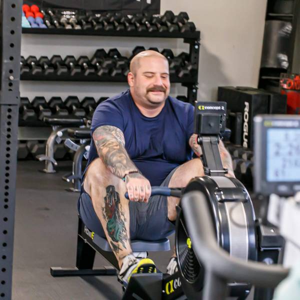 Man performing exercises on machines under the supervision of trainers